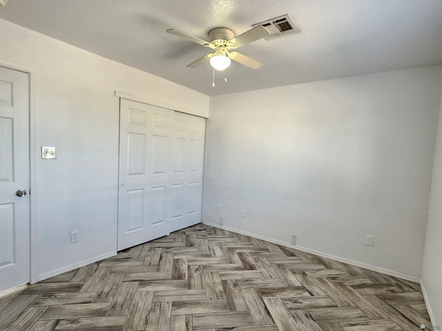 unfurnished bedroom with a textured ceiling, a closet, light parquet flooring, and ceiling fan