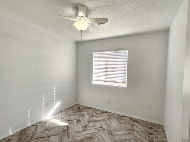 spare room featuring ceiling fan, light parquet flooring, and a textured ceiling