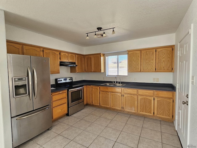 kitchen with sink, a textured ceiling, stainless steel appliances, and light tile patterned floors