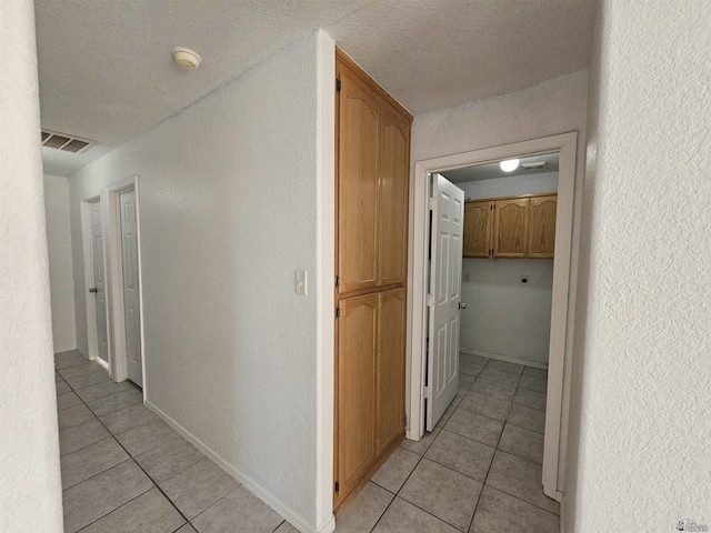 corridor with light tile patterned floors and a textured ceiling