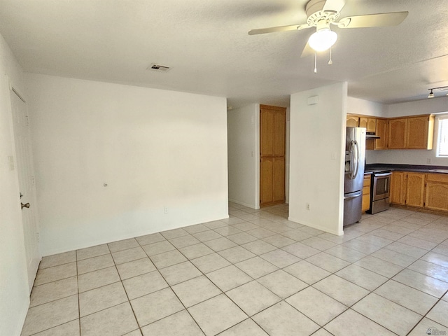 kitchen with ceiling fan, light tile patterned floors, stainless steel appliances, and a textured ceiling