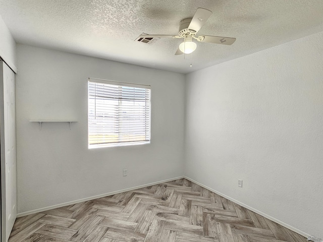 empty room featuring ceiling fan, light parquet floors, and a textured ceiling