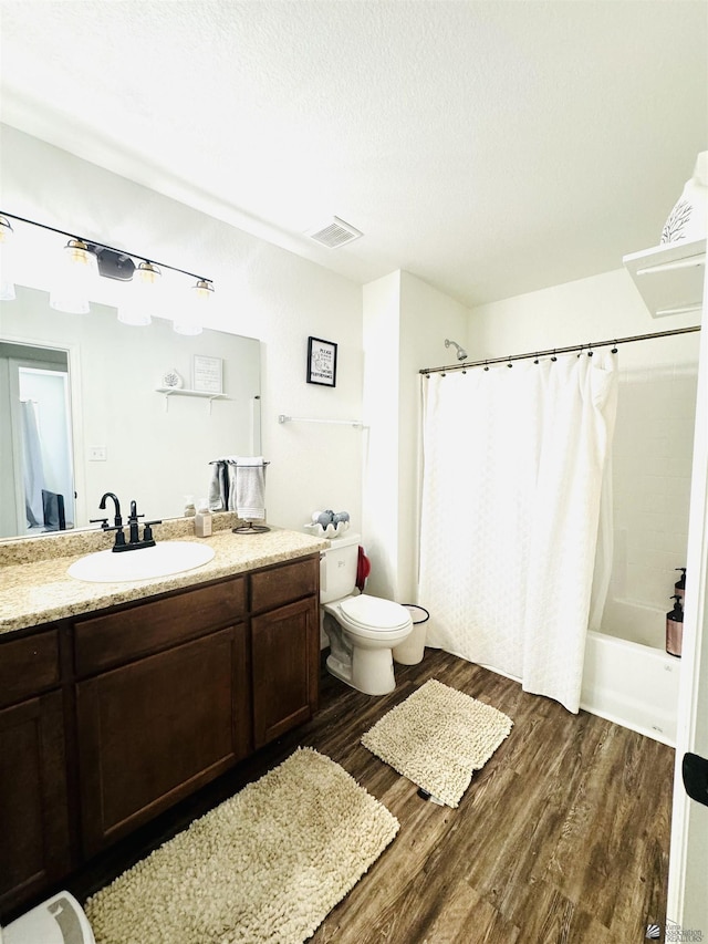 full bathroom featuring hardwood / wood-style floors, vanity, toilet, shower / bathtub combination with curtain, and a textured ceiling