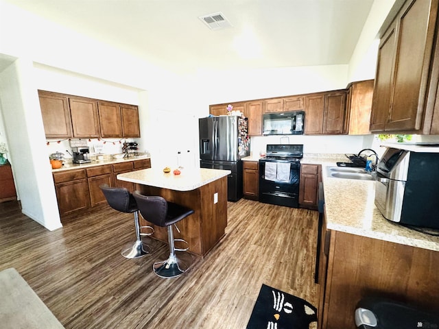 kitchen featuring a breakfast bar, a center island, black appliances, sink, and dark hardwood / wood-style floors