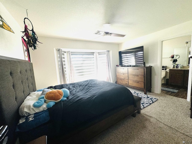 carpeted bedroom featuring ceiling fan, ensuite bathroom, and a textured ceiling