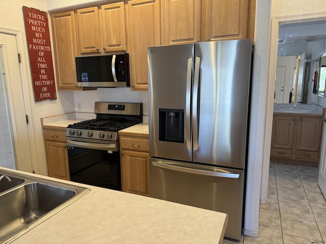 kitchen featuring a sink, light countertops, light tile patterned floors, and stainless steel appliances