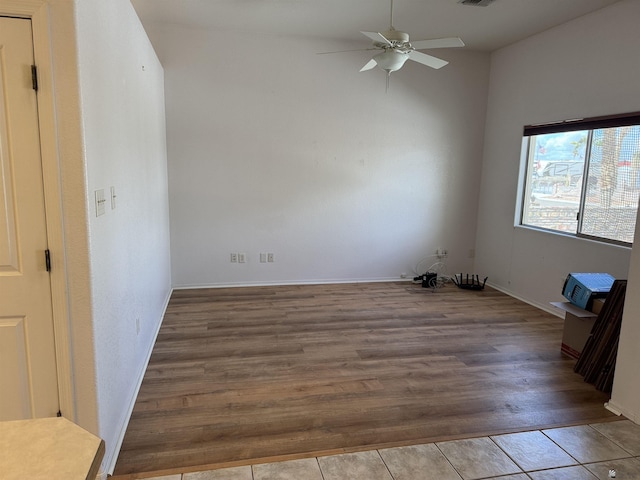 empty room featuring a ceiling fan, wood finished floors, visible vents, and baseboards