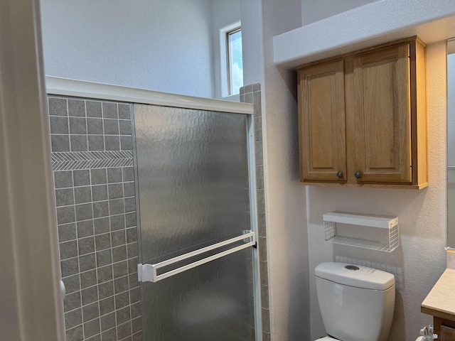 bathroom featuring vanity, a shower stall, toilet, and a textured wall