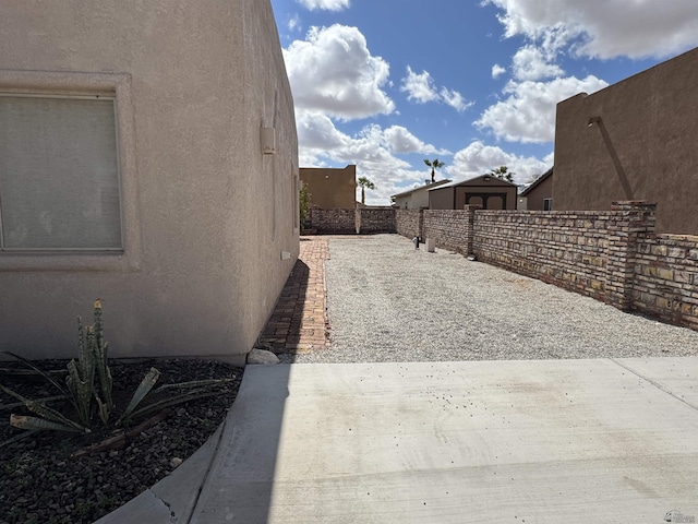 view of side of home with stucco siding, a patio, and fence private yard