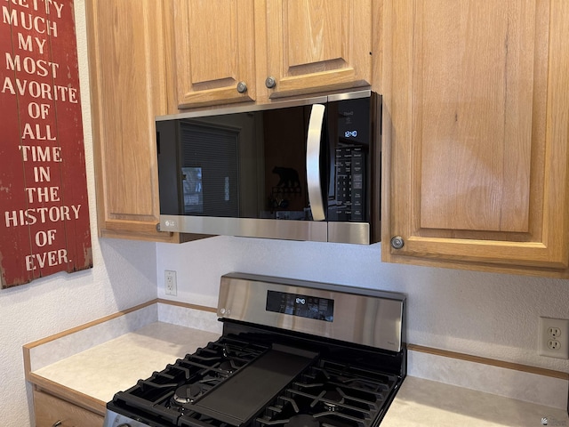 kitchen with appliances with stainless steel finishes, light countertops, and a textured wall