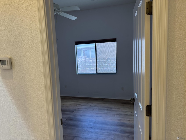 spare room with a textured wall, baseboards, a ceiling fan, and wood finished floors