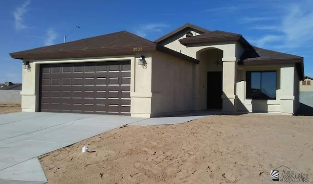 ranch-style home featuring a garage, concrete driveway, and stucco siding