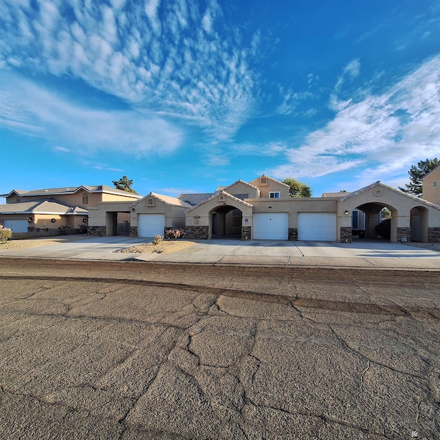 view of front facade with an attached garage, stone siding, concrete driveway, and stucco siding