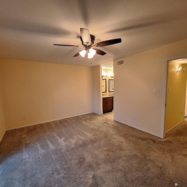 carpeted spare room featuring ceiling fan, a textured ceiling, visible vents, and baseboards