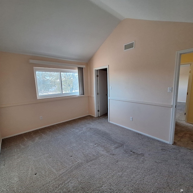 interior space featuring lofted ceiling, baseboards, visible vents, and carpet flooring