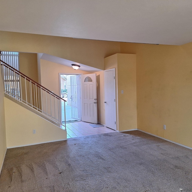 foyer featuring vaulted ceiling, carpet floors, stairway, and baseboards