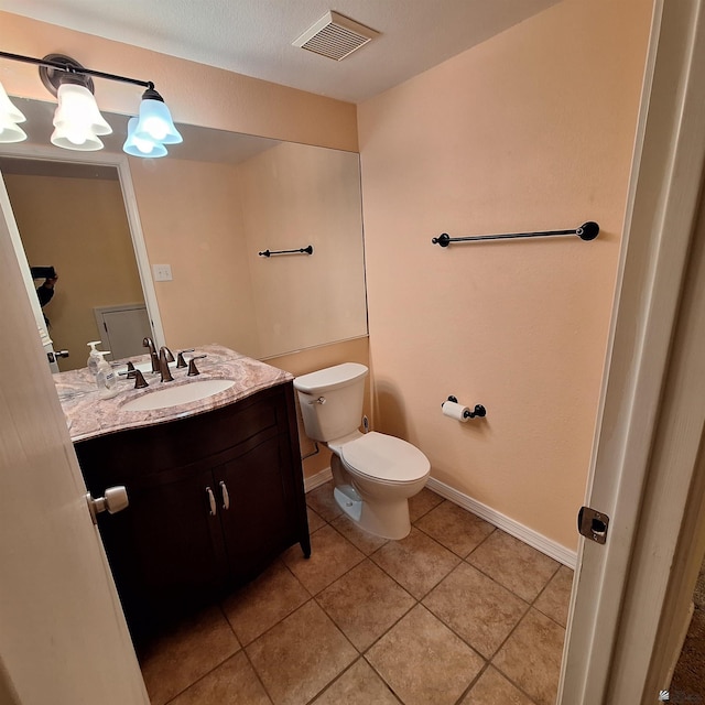 half bathroom with toilet, vanity, baseboards, visible vents, and tile patterned floors