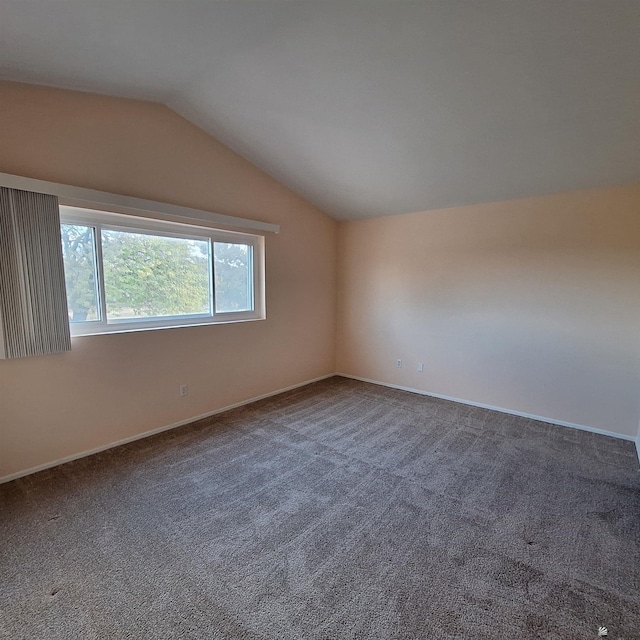 carpeted empty room featuring lofted ceiling