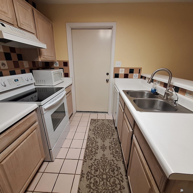 kitchen with white appliances, decorative backsplash, under cabinet range hood, a sink, and light tile patterned flooring