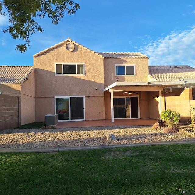 rear view of house with a patio, central AC unit, a tile roof, a lawn, and stucco siding