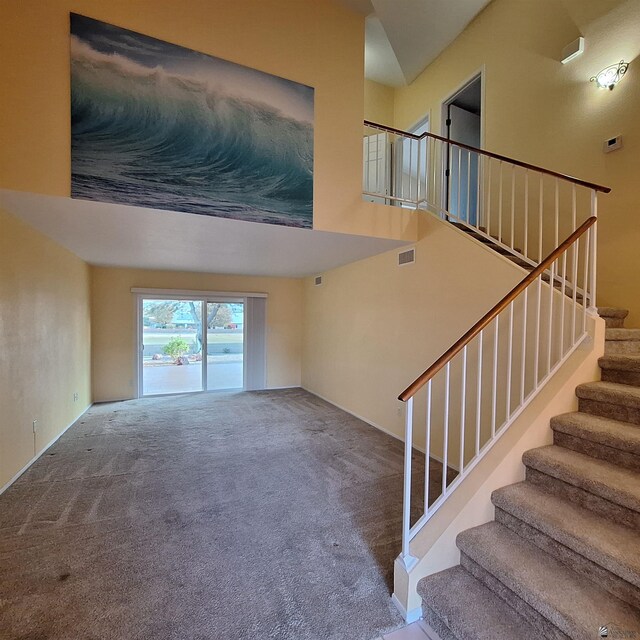 carpeted living room featuring visible vents and stairway