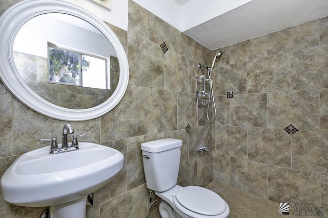 bathroom featuring tiled shower, sink, tile walls, and toilet