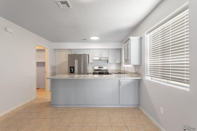 kitchen with sink, kitchen peninsula, light tile patterned floors, and appliances with stainless steel finishes