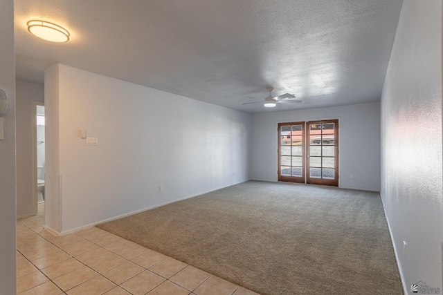 spare room featuring ceiling fan, light colored carpet, and a textured ceiling