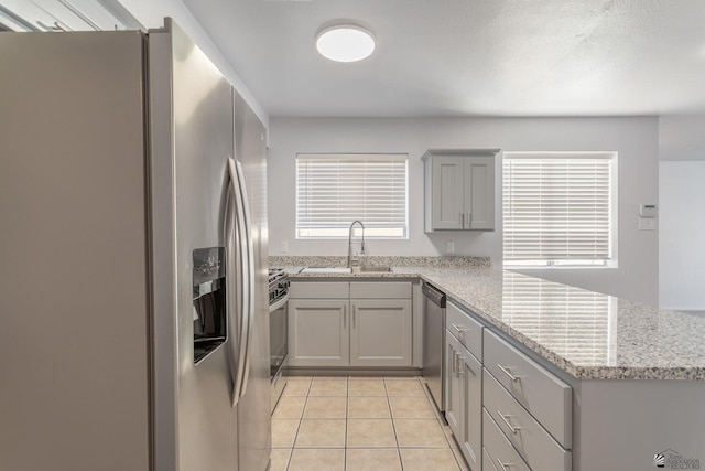 kitchen with sink, stainless steel appliances, kitchen peninsula, and light tile patterned flooring