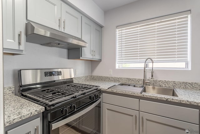 kitchen featuring sink, stainless steel gas range oven, and light stone countertops