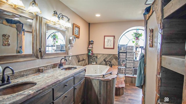 bathroom with hardwood / wood-style floors, a washtub, and vanity