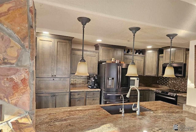 kitchen with appliances with stainless steel finishes, tasteful backsplash, light stone counters, sink, and hanging light fixtures