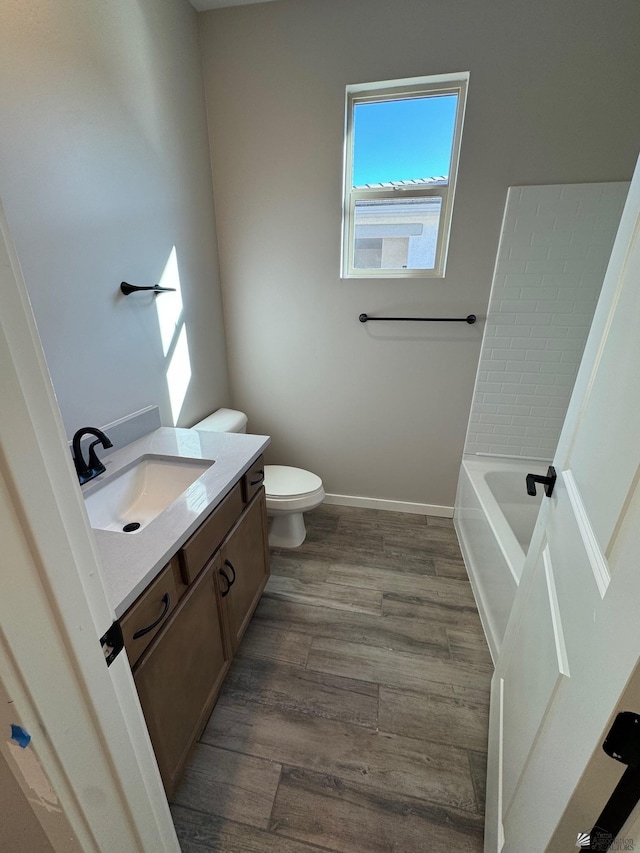 bathroom featuring toilet, vanity, a bathing tub, and hardwood / wood-style floors