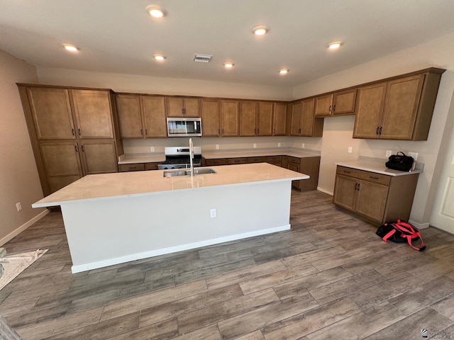 kitchen with appliances with stainless steel finishes, sink, and a kitchen island with sink