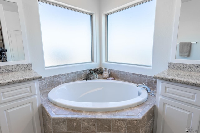 bathroom with tiled tub and vanity