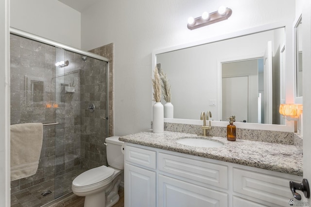 bathroom featuring toilet, vanity, and walk in shower