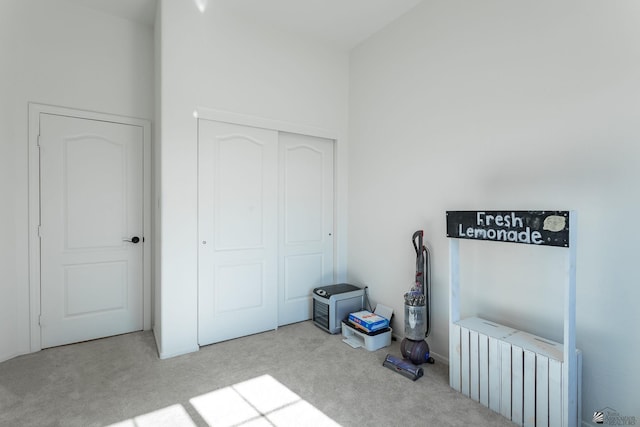 bedroom featuring light carpet, a towering ceiling, a closet, and radiator