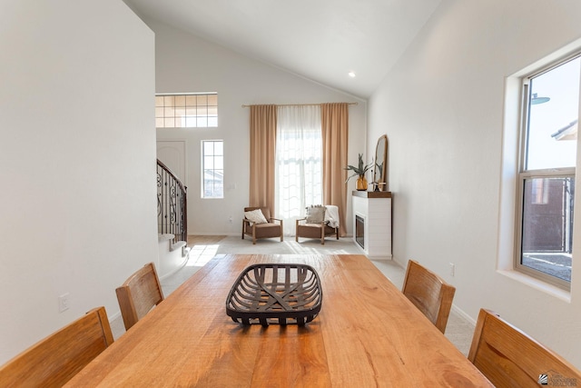 dining space featuring high vaulted ceiling and light carpet