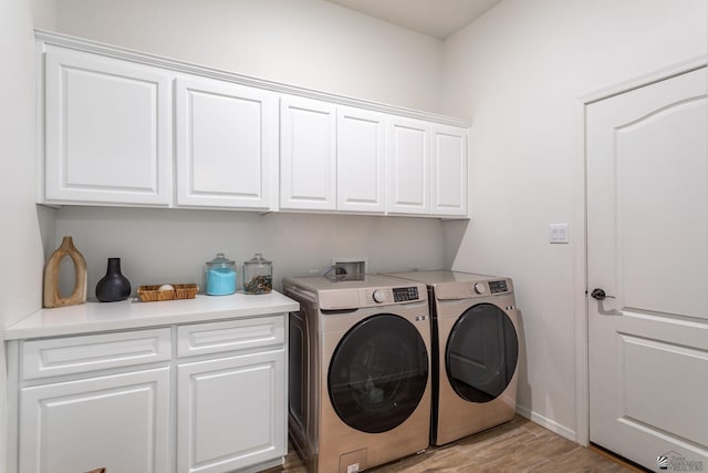 clothes washing area featuring cabinets, washer and clothes dryer, and light hardwood / wood-style floors