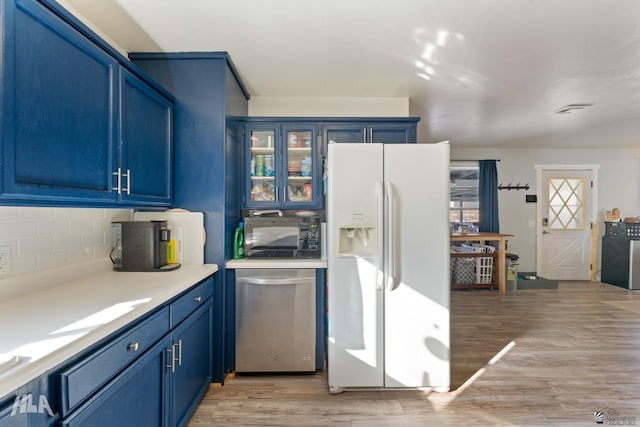 kitchen with white refrigerator with ice dispenser, light hardwood / wood-style flooring, and blue cabinets