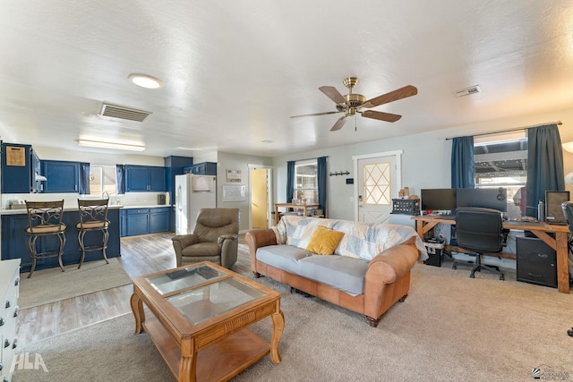 living room featuring a textured ceiling, light hardwood / wood-style flooring, and ceiling fan