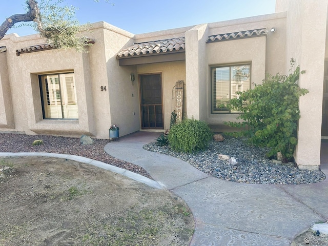 view of exterior entry featuring a tile roof and stucco siding