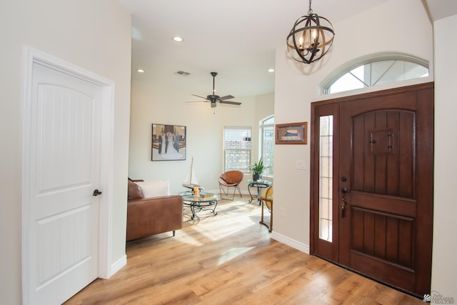 entryway featuring ceiling fan with notable chandelier, a healthy amount of sunlight, and light hardwood / wood-style flooring