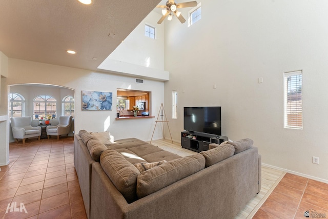 living room with a high ceiling, ceiling fan, and tile patterned floors