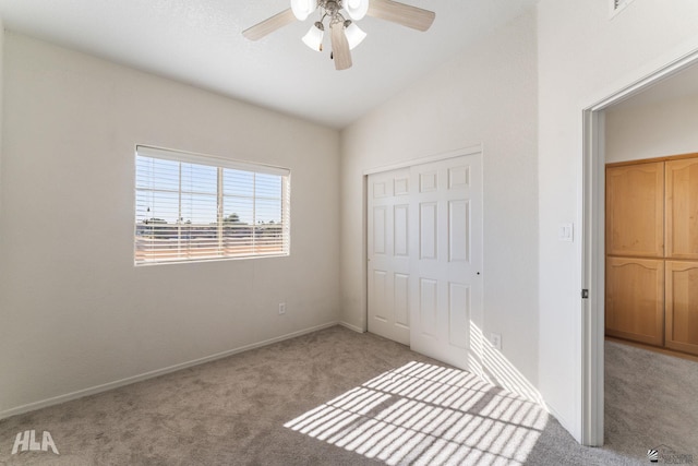 unfurnished bedroom featuring a closet, ceiling fan, vaulted ceiling, and carpet floors