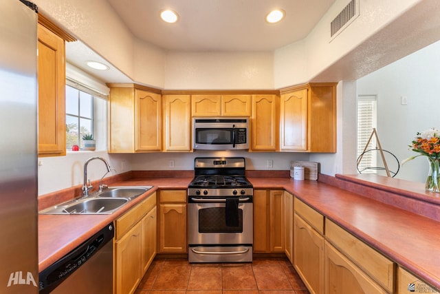 kitchen featuring stainless steel appliances, dark tile patterned floors, sink, and light brown cabinets