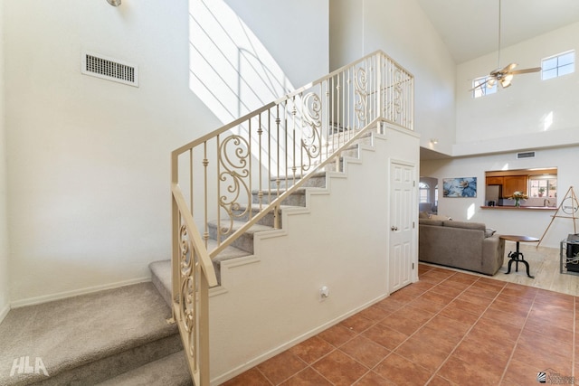 stairs featuring ceiling fan, tile patterned flooring, and a towering ceiling