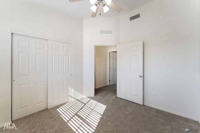 unfurnished bedroom featuring ceiling fan, a closet, and dark colored carpet