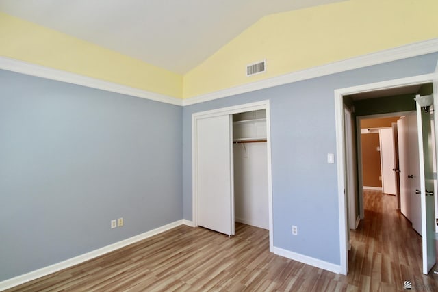 unfurnished bedroom with light hardwood / wood-style floors, vaulted ceiling, and a closet