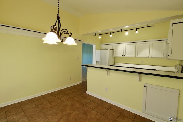 kitchen with a chandelier, vaulted ceiling, pendant lighting, white refrigerator with ice dispenser, and white cabinets